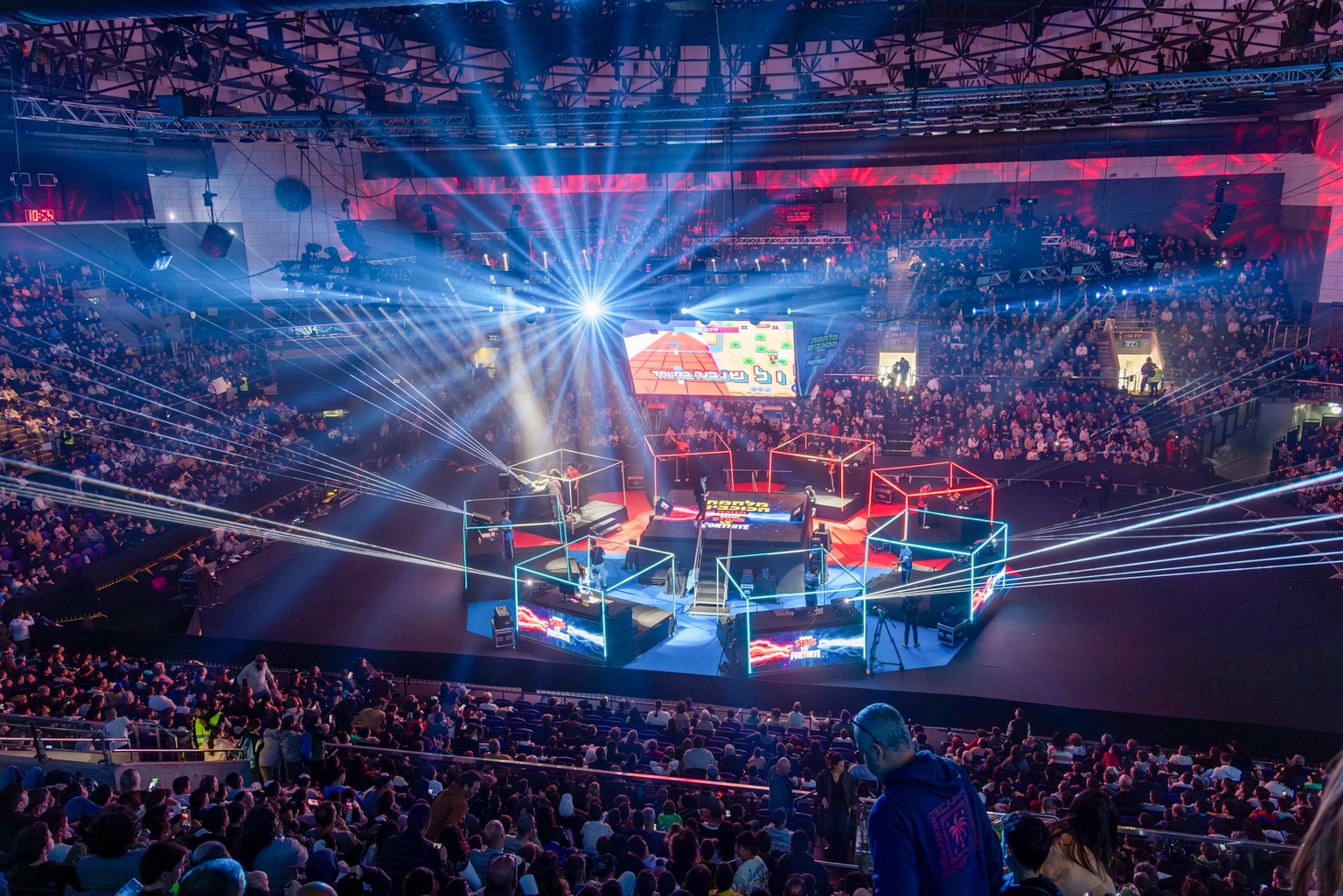 A packed arena surrounding a live stage production at Toto Hall Holon